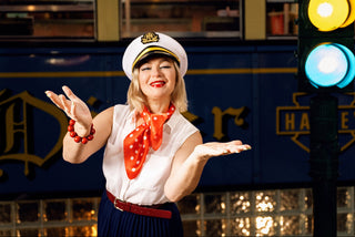 Person in a vintage uniform with a traffic light and train in the background