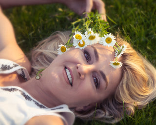 Woman lying on grass with a flower crown, smiling.