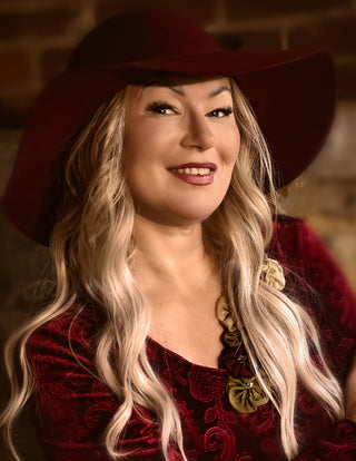Woman wearing a red hat and red dress with floral details against a brick wall.