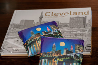 Two Cleveland-themed pouches on a book titled 'Cleveland Then and Now' on a wooden surface.
