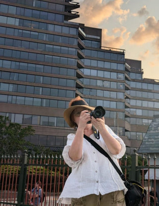 Person taking a photo with a camera in front of a modern building